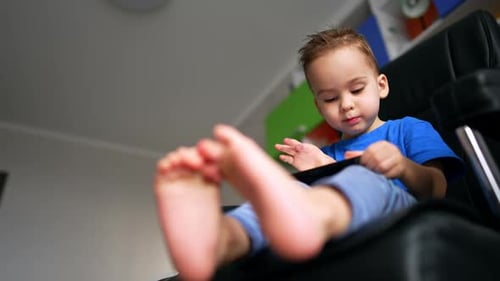 Child Using Smartphone in Chair at Home