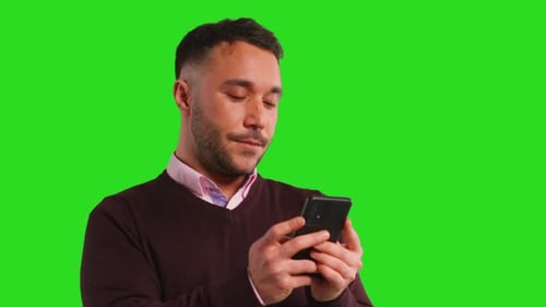 Close Up Studio Shot Of Businessman Using Mobile Phone Or Browse Online Standing Against GreenScreen