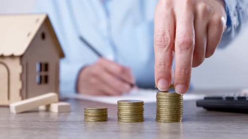 Saving money to buy a house. Coins in a woman's hand as an investment in real estate.