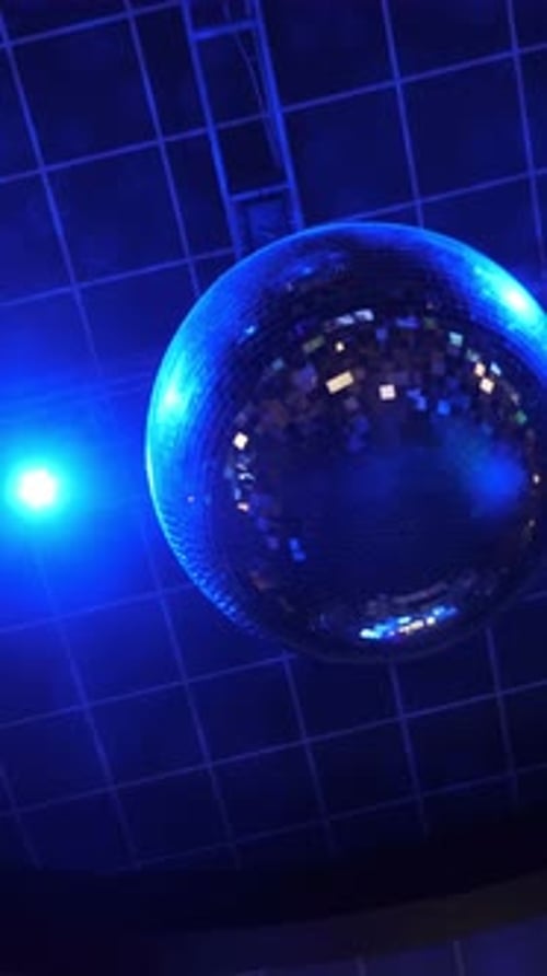 Shimmering Disco Ball Catches Blue Light at Lively Dance Floor During Evening Celebration