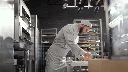 Handsome Caucasian Man in White Uniform Cutting Dough and Shaping Cookies in Bakery Baking Concept