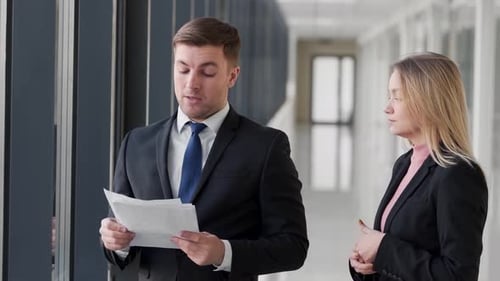 Businesspeople Discussing Documents in Office Hallway