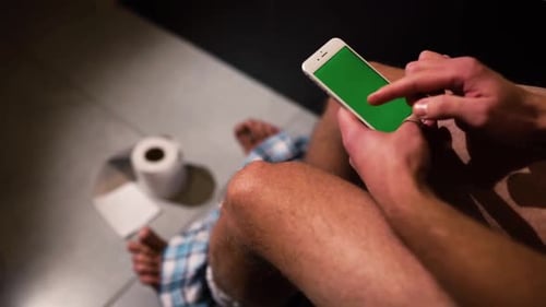 Video of Man with Pants on Feet Turning Phone on in Hands and Start Using It Swiping Up Down and