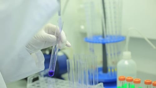 Researcher extracts liquid into test tube in lab