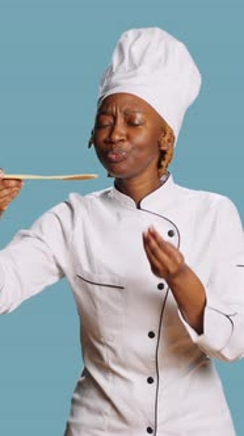Chef Tasting Food Off Wooden Spoon Approves