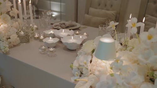 Eleganter weißer Blumenhochzeitstisch mit leuchtenden Kerzen