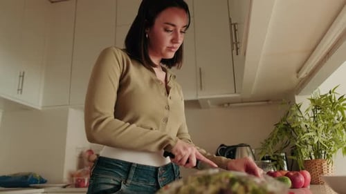 Woman Cutting Vegetables in Sunny Kitchen
