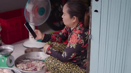 Woman Looks at Phone Crouching in Doorway