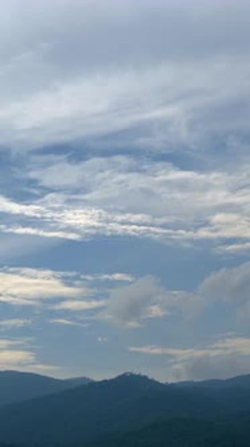 Blue sky with cumulus cloud time lapse over a mountain.