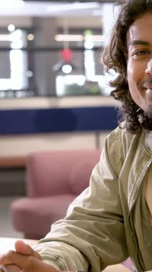 Vertical video: Camera zooming as man in jacket with watch leaning, smiling in lounge, copy space