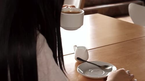 Charming Girl Savoring Coffee at a Cozy Cafe