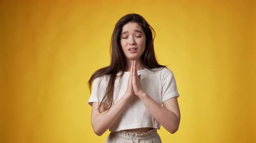 Young Woman Pleading with Hands Clasped Together