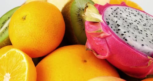 Fruit basket with dragon fruit pitahaya, kiwi, oranges, bananas and apples on a white background.