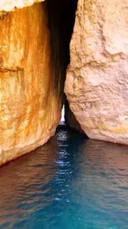 Cave in the cliffs in the Mediterranean Sea. Rocks at the coast of Malta, Europe. Vertical video.