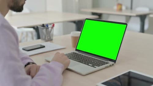 Rear View of Man Working on Laptop with Green Chroma Screen