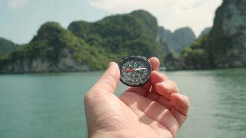 Hand Holding Compass Near Tropical Island