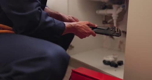 Plumber repairs leaky drain under the sink