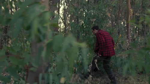 Axe Killer Man Walks Through the Trees in the Forest to Find Victims