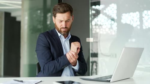 Business Man Massages His Wrist in Office