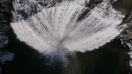 Un Zumbido aéreo captura una majestuosa cascada que cae en cascada por una montaña rocosa en Islandia, con el agua