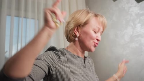 Femme joyeuse dansant joyeusement dans une pièce lumineuse avec les bras levés