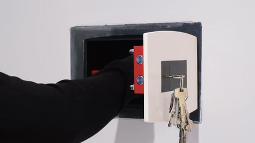 Gloved Hand Hides Money in Wall Safe