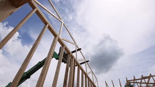 Bauarbeiter nutzen Teleskoplader, um Holzbalken auf der Baustelle unter blauem Himmel zu heben
