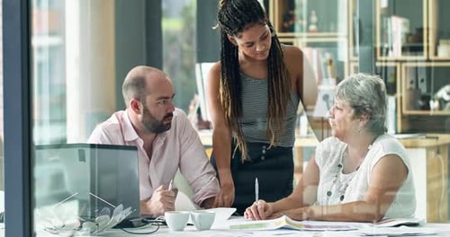 4k video footage of a diverse group of colleagues talking together over paperwork in an office