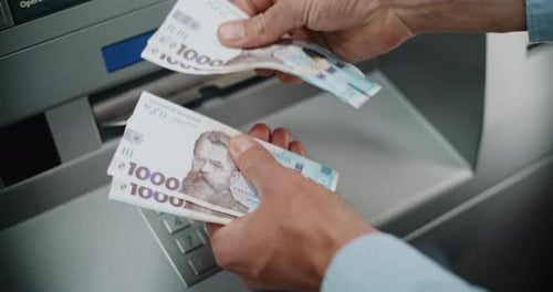 Close Up of Man Counting Hryvnia Bills After Withdrawing Cash Money From ATM Machine