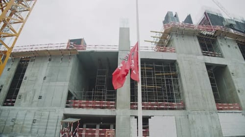 Bandeira da empresa acenando em poste alto perto de prédio de concreto