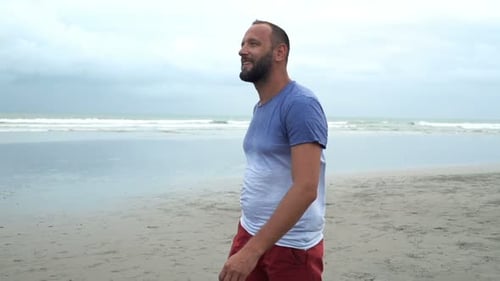 Young man enjoying summer holidays walking on tropical beach in super slow motion