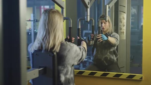 Sports Girl Performs Exercises on the Simulator in the Gym