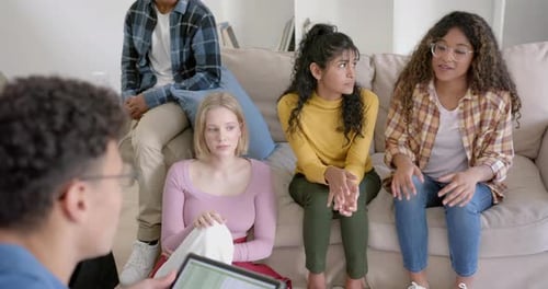 Groupe diversifié et attentionné d'amis adolescents utilisant une tablette et parlant à la maison, au ralenti