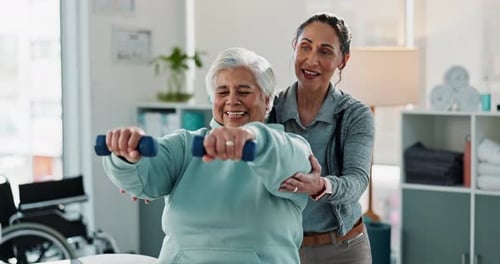 Senior Woman Lifting Weights Assisted by Fitness Trainer