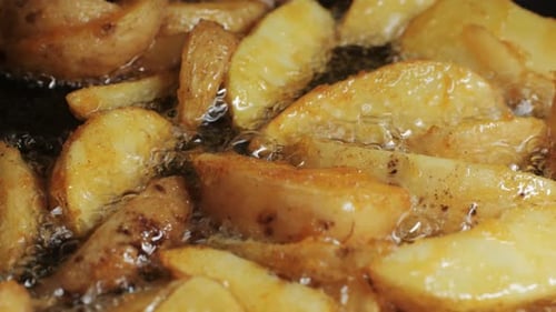 Making Fried Potato Wedges Country Potatoes in a Pan in Boiling Oil Closeup Potato Pieces Snack Food