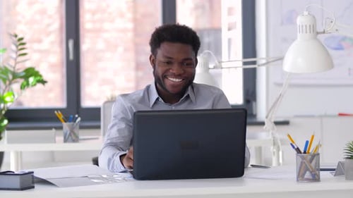 Excited man video conferencing on laptop in office