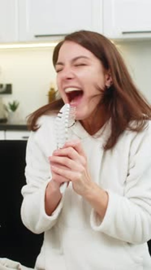 Woman Singing and Dancing with Hairbrush in Kitchen