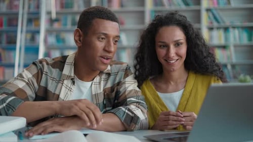 Two Young Adults Studying Together in a Library