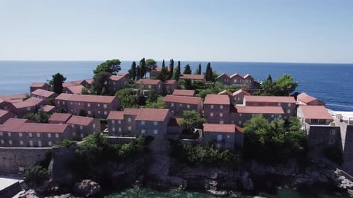 A drone flies over the island of Sveti Stefan on a sunny day in Montenegro
