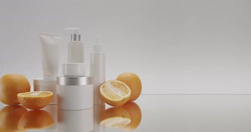 Bottles with Fresh Orange Fruits for Beauty Treatment on a White Background