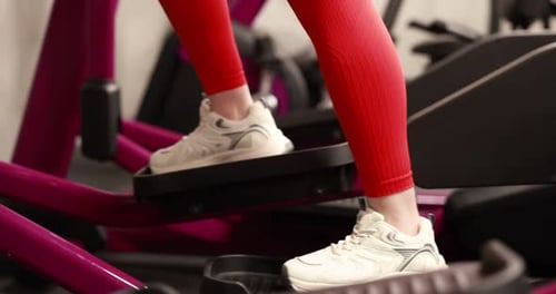 Strong woman training on elliptical machine in gym, closeup
