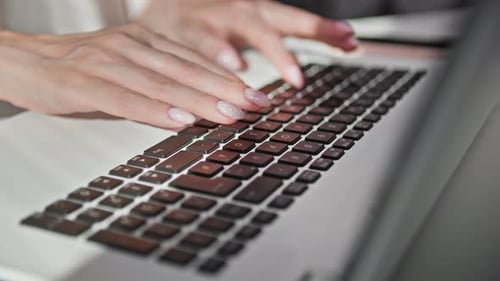 Female Hand Typing on Keyboard of a Laptop Computer Sitting at Table Top View