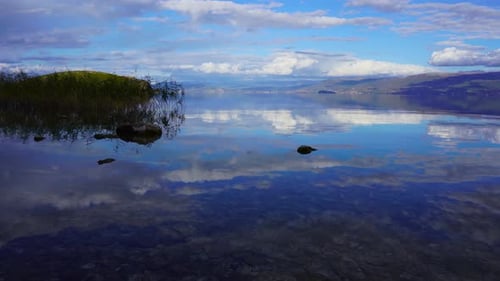 Calm mirror water surface reflecting beautiful sky with clouds on blue colors at twilight