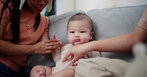 Loving Adults Interact with Adorable Infant on Couch