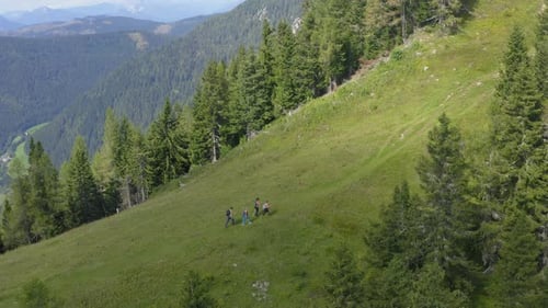 Drone shot of four hikers walking on a hill with a wide mountain shot in the background.