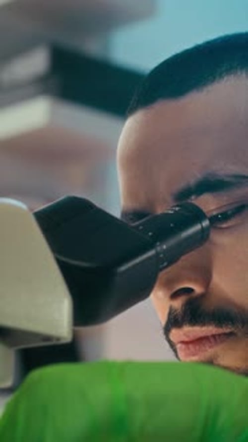 Man Works with Microscope in Medical Lab
