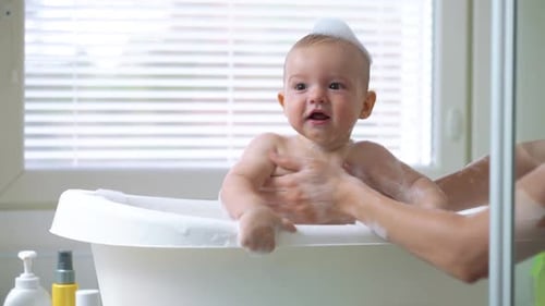 Infant enjoying bath time in sunny bathroom