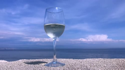 A chilled white wine glass with condensation sits elegantly on a stone surface, set against the sere
