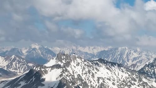 Air flight through mountain clouds over beautiful snow-capped peaks of mountains and glaciers.
