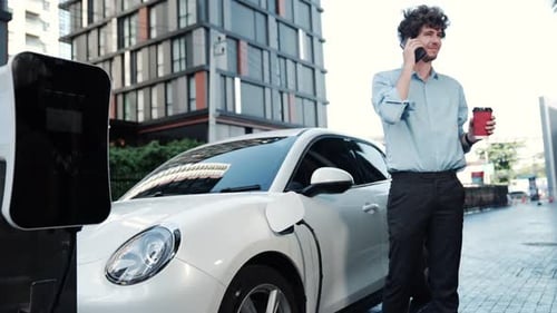 Geeigneter Geschäftsmann mit fortschrittlichem Ehrgeiz stützt sich auf sein Elektrofahrzeug